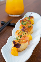 Delicious pan seared organic scallops, served with freshly sliced oranges. Presented professionally and shot with a shallow depth of field.