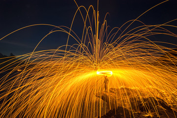 Showers of hot glowing sparks from spinning steel wool on the rock and beach