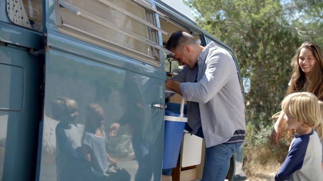 Family packing up their camper van for a road trip vacation