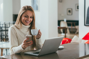 Young business woman drinking coffee and texting on mobile phone