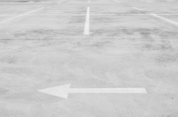 Closeup surface old and pale white painted arrow sign and line slot for parking on cement street floor in the car park textured background with copy space