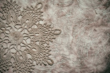 beige neutral crochet doily close up on a beige cement background with copy space. needlework concept.