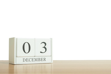 Closeup surface white wooden calendar with black 3 december word on blurred brown wood desk isolated on white background with copy space , selective focus at the calendar