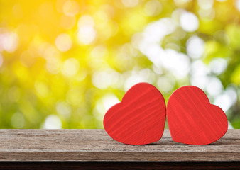 Red hearts on wooden table against defocused lights