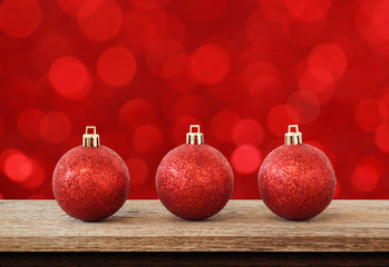 Red christmas ball on wood table top over red background with a light blur