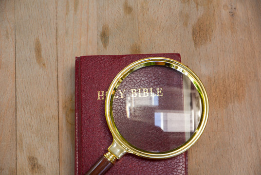 bible book and magnifying glass on wood background