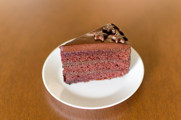 Piece of dark chocolate cake on white dish ready to eating