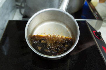 A hot pan of boiling coffee, on and industrial chefs heating stove, in a kitchen.