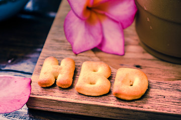 iced coffee and biscuit alphabet spell HBD with rice field backg