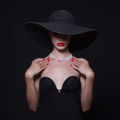 A necklace of diamonds on the neck of a luxurious woman in a hat.