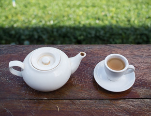 Top shot - Cup of tea and teakettle on wooden bar. Beauty nature background of tea plantation at Doi-Montngo , Chiang Mai, Thailand