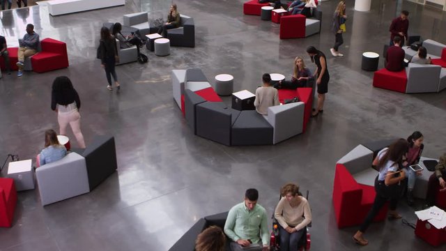 Elevated pan shot of students in busy university lobby area, shot on R3D