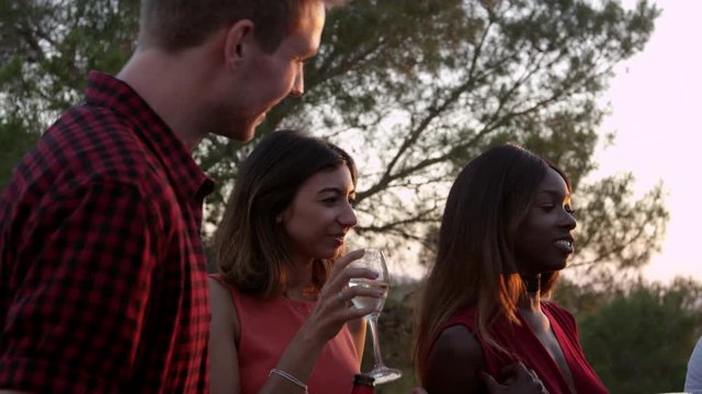 Adult friends socialising at a party on a rooftop at sunset, shot on R3D 