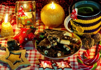 Christmas arrangement with candles, chocolate with nuts, chocolate bars, anise stars, dry tea, decoration, candle, candy, cup in knit cover. Postcard Merry Christmas