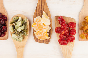 Assortment of dried fruits on wooden spoons on white background. Decorative border of dry exotic fruit. Top view.