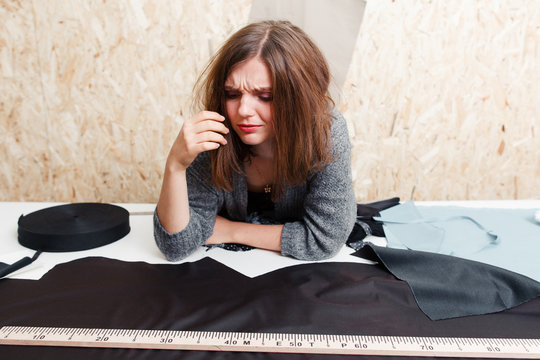 Overworked designer crying above fabric. Stressed tailor preparing material for sewing clothes. Garment industry, tailoring process, pattern cutting concept