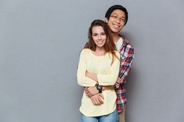 Smiling young interracial couple hugging and looking at camera