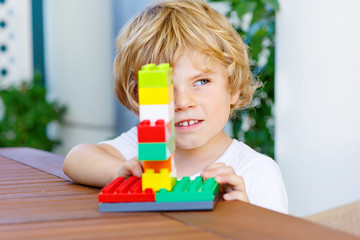 Little kid boy playing with colorful plastic blocks
