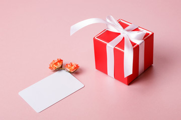 Valentine day composition: red gift box with bow, credit / visiting card template and spring flowers on light pink background.