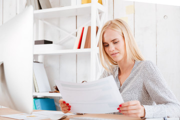 Business woman holding documents while sitting at her workplace