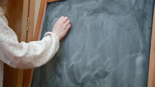 Girl writing E=MC2 on blackboard