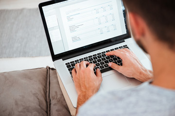 Cropped image of man typing by laptop. Focus on hands