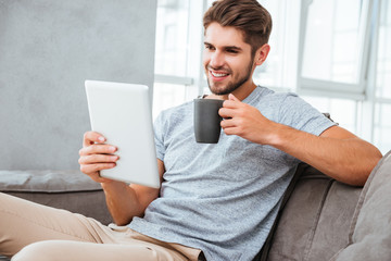 Cheerful man communication by tablet while drinking a coffee