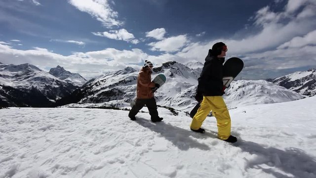 Two men carrying snowboards in ski resort