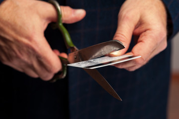Male hands wirh scissors cutting bank credit card