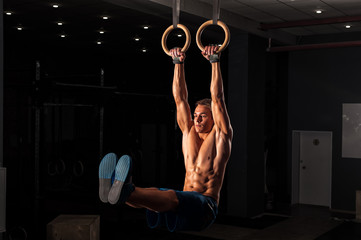 Muscular young adult on gymnastics rings