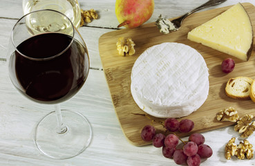 Wine, cheese, grapes and nuts on wooden board