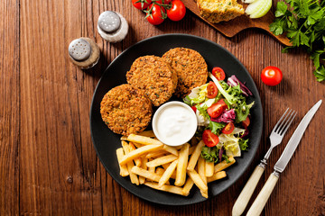 Serving of falafel and chips served on a black plate with sauce.
