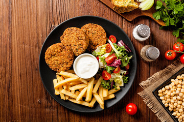 Serving of falafel and chips served on a black plate with sauce.