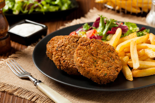 Serving of falafel and chips served on a black plate with sauce.