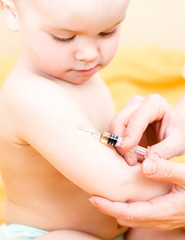 Close-up shot of pediatrician giving an intramuscular injection of a vaccine to a baby girl