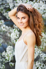 Naklejka premium Young beautiful woman in white dress enjoying of blooming tree
