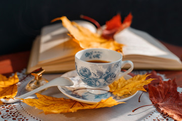 coffee Cup and book on a table on a background of yellow leaves
