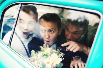 Cheerful groomsmen and a groom in the old-fashioned car