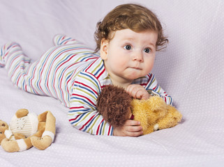 The little boy in the crib with toys. The child in the home
