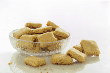 Fototapeta na wymiar biscotti casalinghi di frolla in ciotola di vetro su piano bianco traslucido