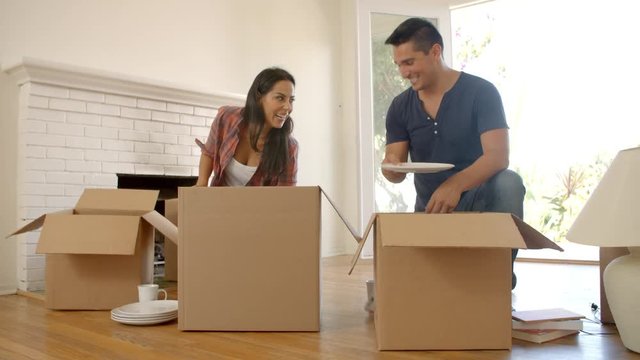 Couple Unpacking Boxes In New Home On Moving Day