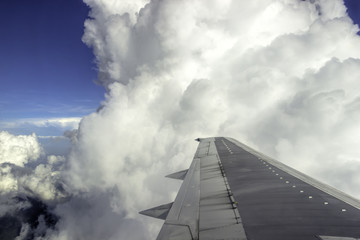 Airplane wing almost scratching a blue cloud