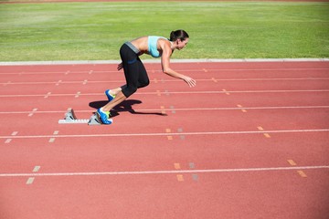 Obraz premium Female athlete running from starting blocks