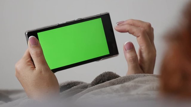Modern redhead woman with chroma key greenscreen tablet 4K 2160p 30fps UHD footage - Female holding green screen smart phone while in bed 3840X2160 UltraHD video 