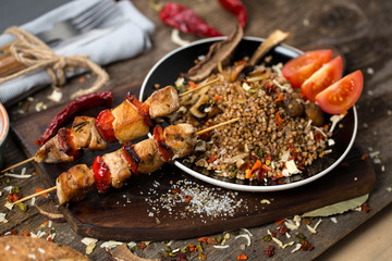 Buckwheat with sauce and chicken kebabs on skewers on a plate
