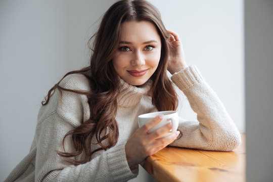 Smiling woman in sweater with tea