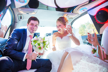 Happy newlyweds celebrate their wedding in limousine - obrazy, fototapety, plakaty