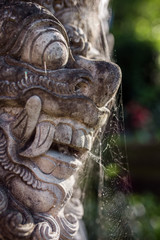 Fototapeta na wymiar Traditional guard demon statue carved in dark stone on Bali island
