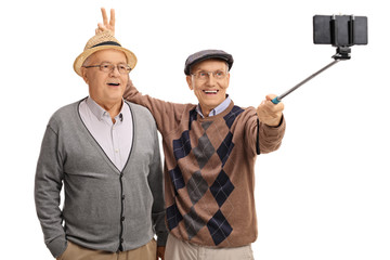 Elderly man pranking another man with bunny ears and taking self