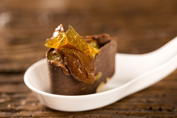 Base of biscuit, mango and passion fruit gel, half bitter chocolate mousse with orange and passion fruit glass in a spoon. Taste gastronomy fingerfood